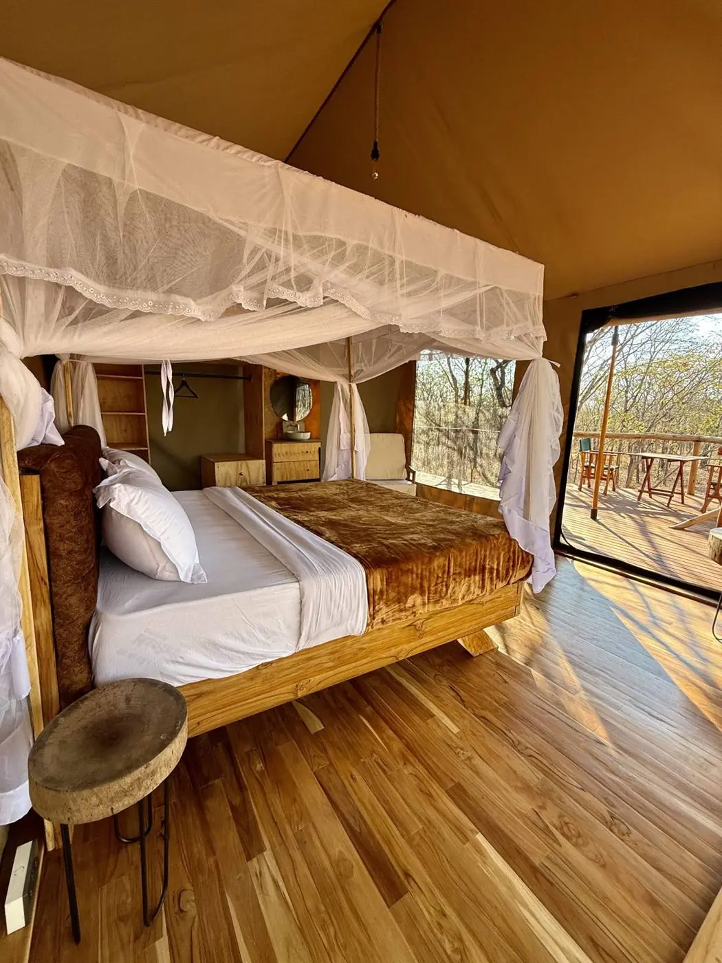 Luxury safari tent at Camp Lilac on a raised wooden deck under the trees near Mikumi National Park